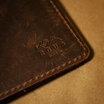Close-up of a brown notebook journal cover with a brand logo on a beige background