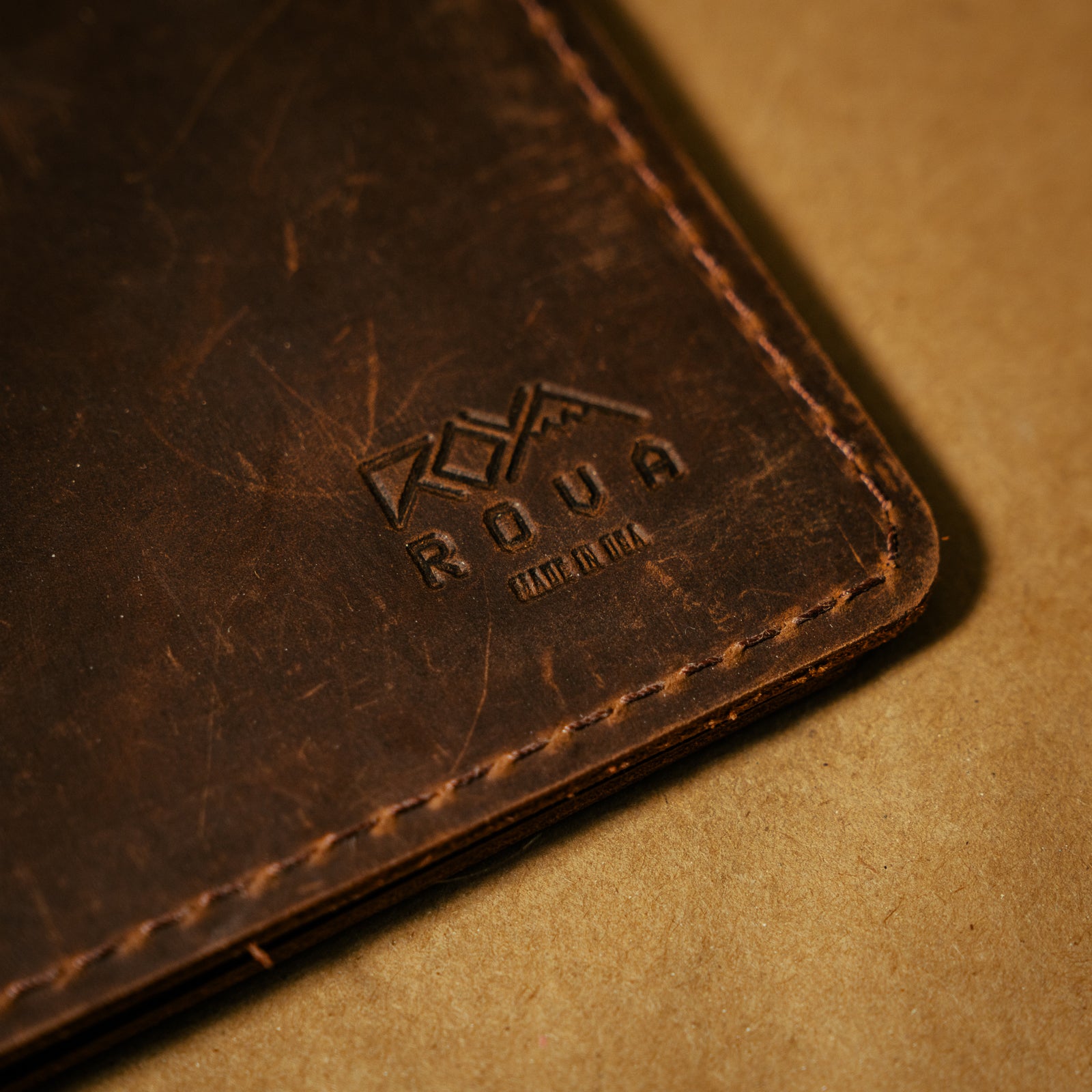 Close-up of a brown notebook journal cover with a brand logo on a beige background
