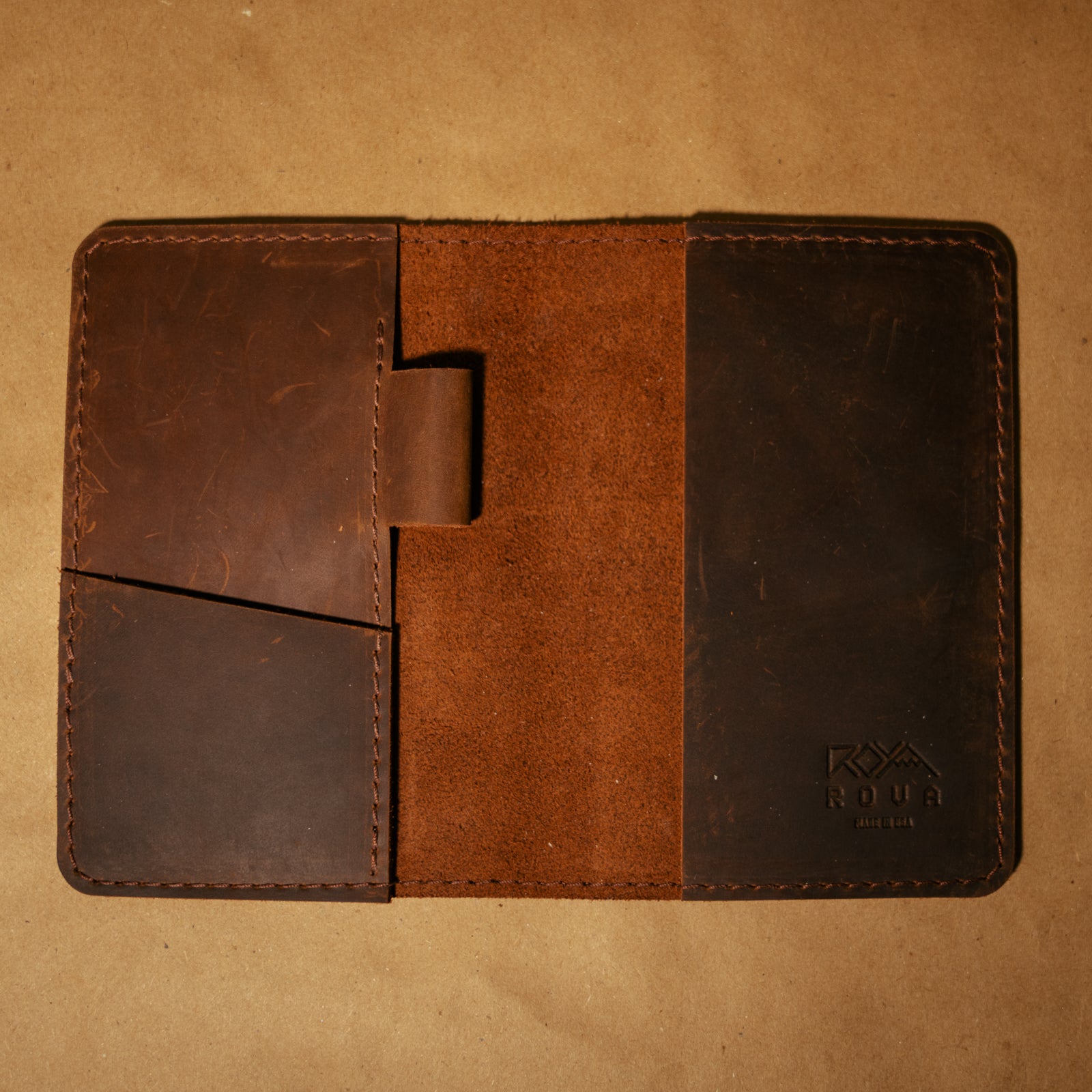 Brown leather field notes notebook cover with visible brand logo on a beige background