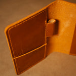 Close-up of a whiskey orange leather field notes cover on a matching background