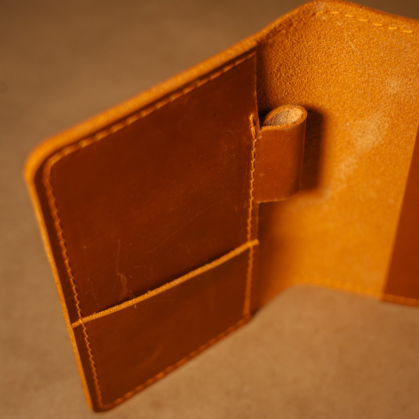 Close-up of a whiskey orange leather field notes cover on a matching background