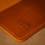 Close up of a whiskey orange leather field notes cover with branding.