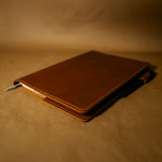 Brown full grain leather notebook cover on a matching brown background