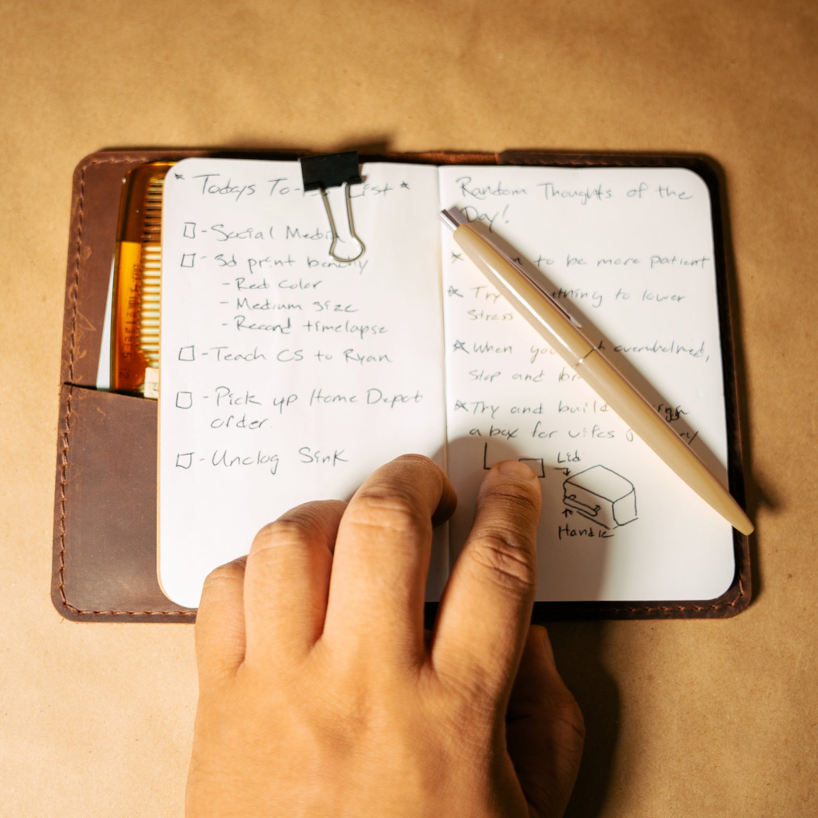 Handwritten to-do list in a leather field notes notebook cover with a pen on a beige background