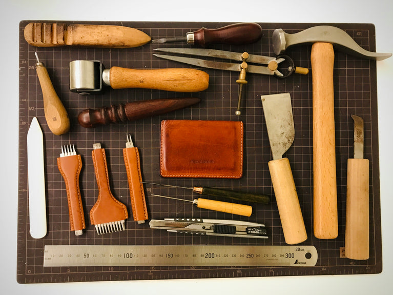 Set of leatherworking tools on a cutting mat with a ruler.